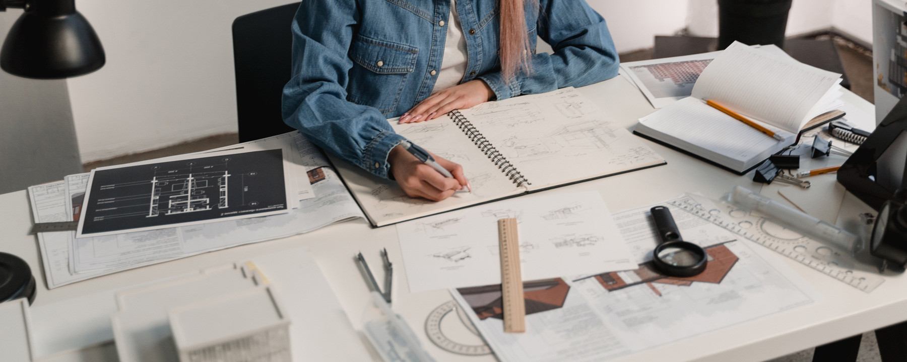 An architect sits at a desk with paper work and drawings.