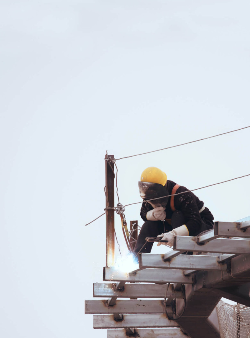 A construction worker welding together a metal frame.