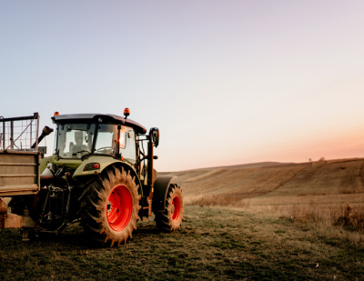 A tractor sits in a field at sunset.
